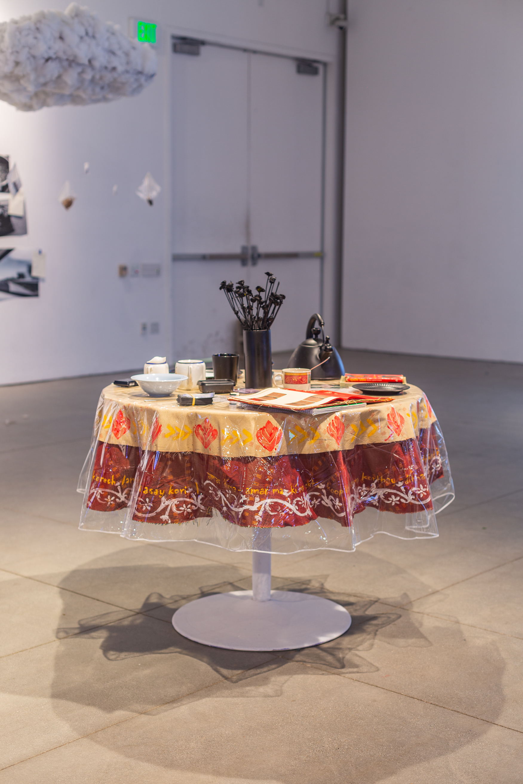 round table with assorted homeware, a vase in the middle with black flowers and a book in the front